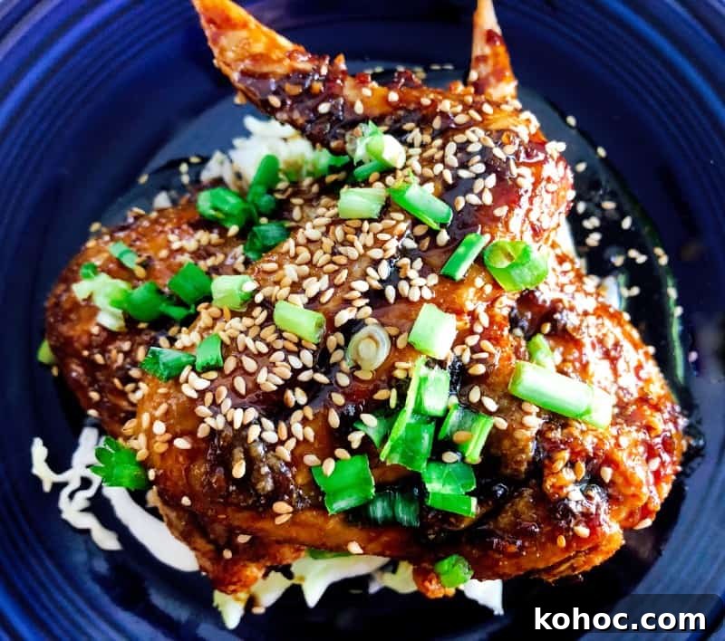 Crispy Oven-Baked Asian-Style Chicken Wings for Game Night 9 Crispy Baked Asian Chicken Wings on a plate with chopped green onions and baked sesame seeds for garnish.