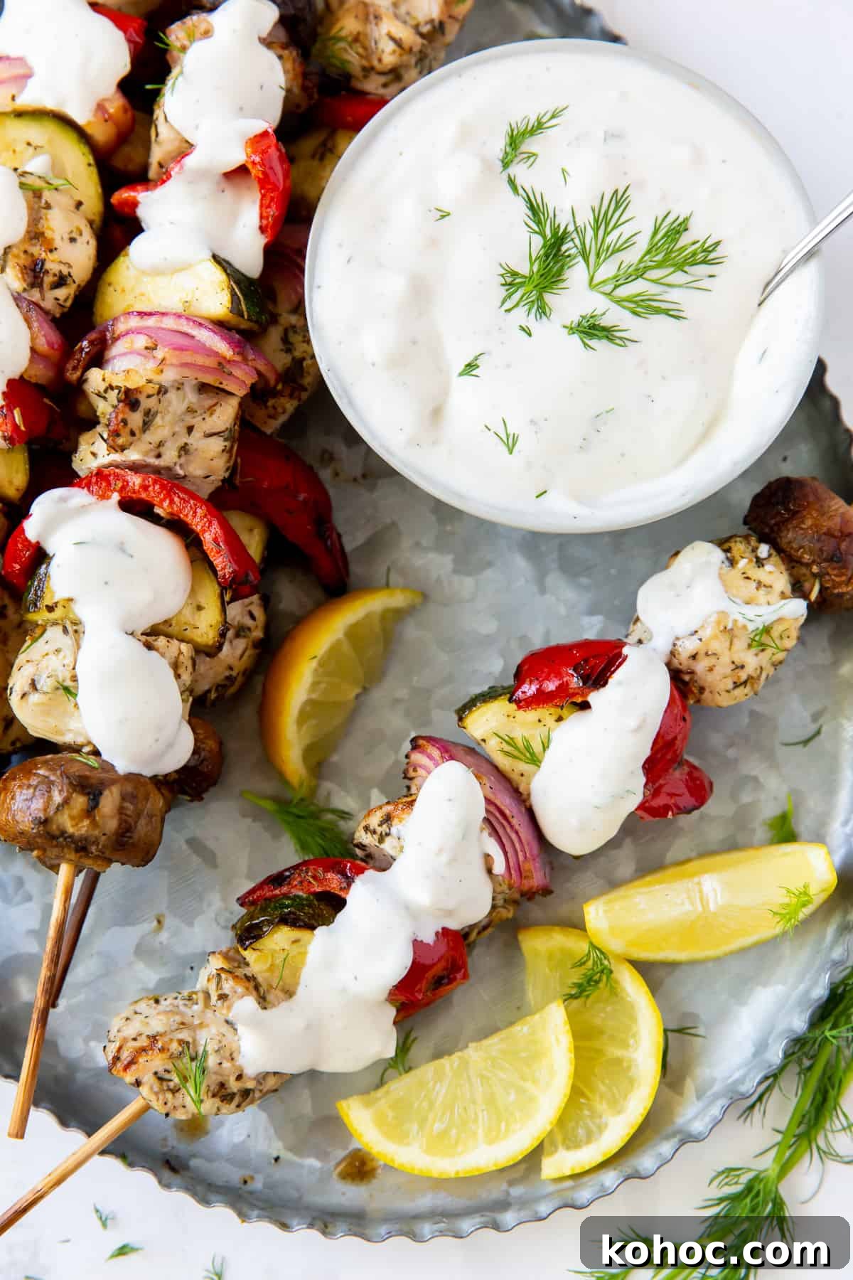 Greek Chicken Kabobs Recipe with Tzatziki and Grilled Vegetables 3 Greek Chicken Kabobs with Feta Dill Sauce spooned over the top.