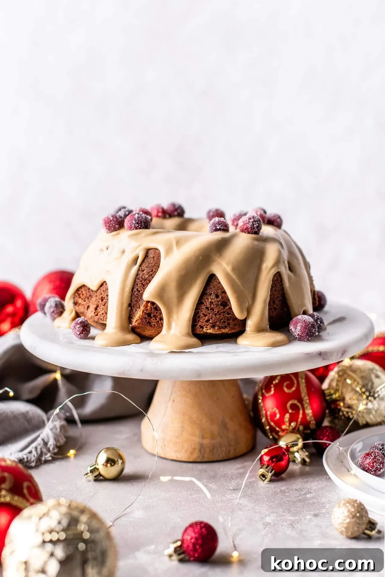 Caramel Gingerbread Cake with Silky Whipped Caramel Icing 2 frosted caramel gingerbread cake decorated with sugared cranberries on cake stand (1)