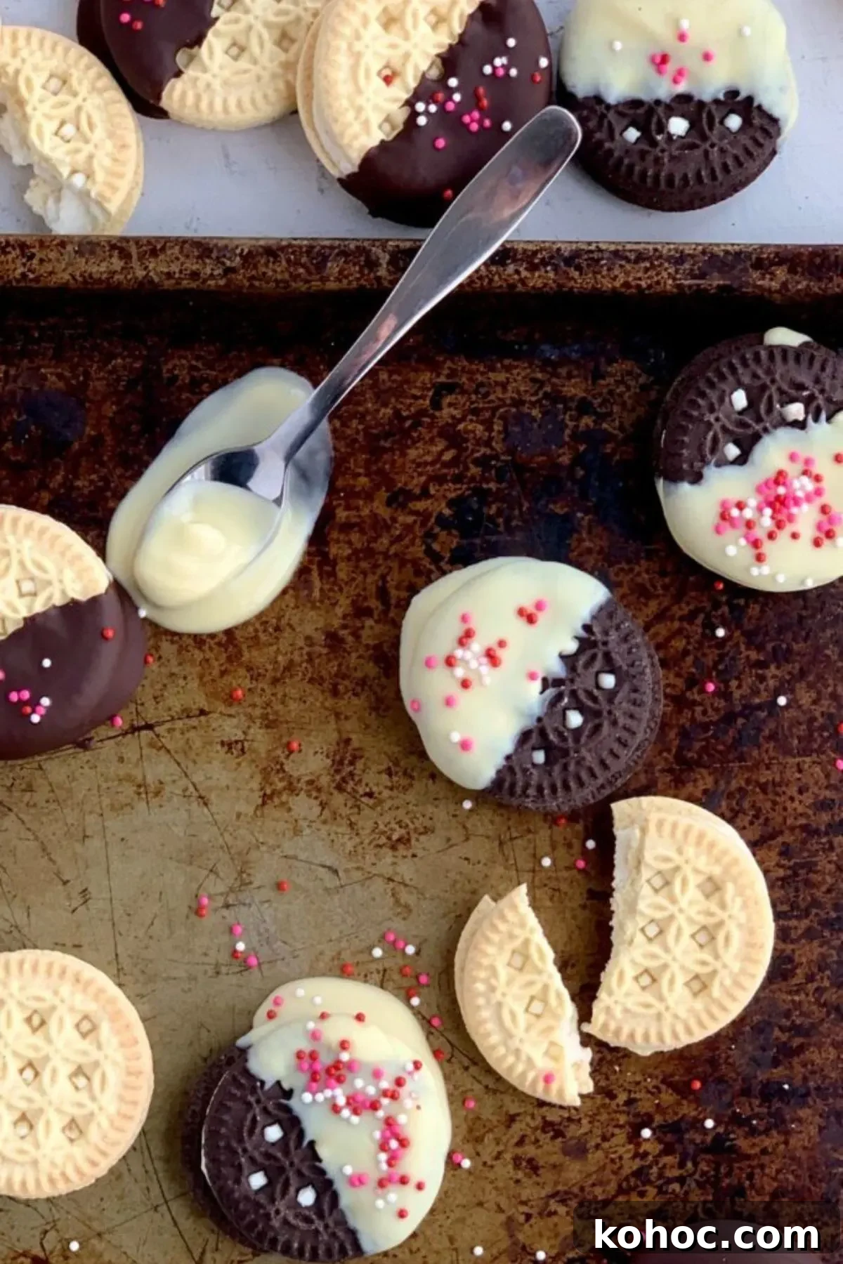 A spoon with melted dairy free chocolate on a baking sheet with more coated cookies.