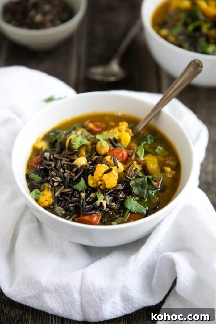 Turmeric Vegetable and Wild Rice Broth Soup 4 White bowls filled with vegetables, lentils, garbanzo beans, and wild rice, and fresh cilantro.