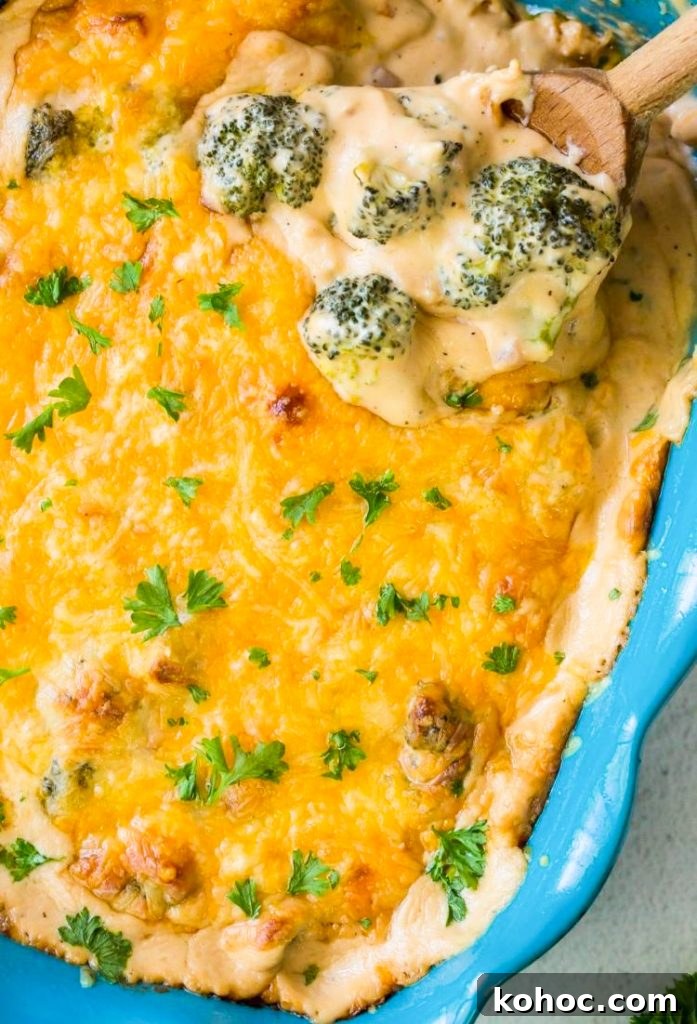 keto broccoli and cheese casserole in a blue baking dish with a wooden spoon, green napkin and parsley 