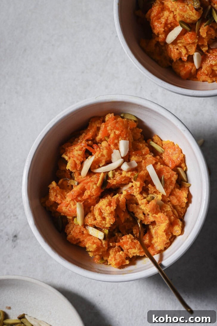 Close up of bowls of Carrot Halwa garnished with slivered almonds and pistachios ready to be eaten.