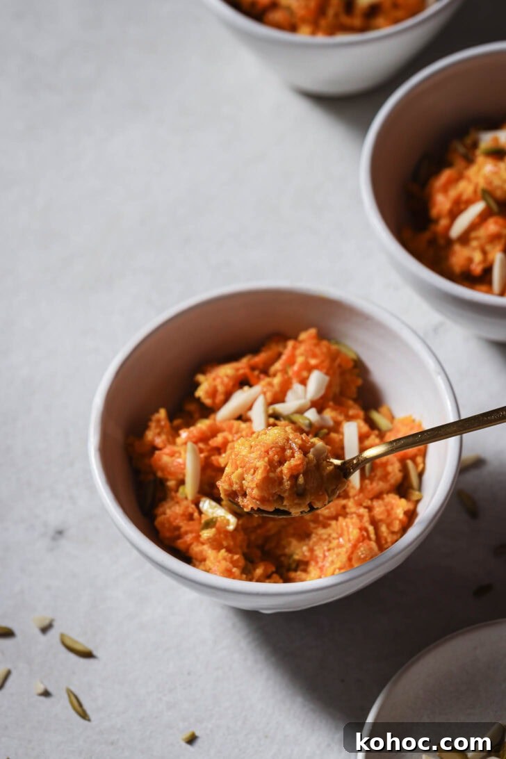 Holding a spoonful of Carrot Halwa over a bowl.