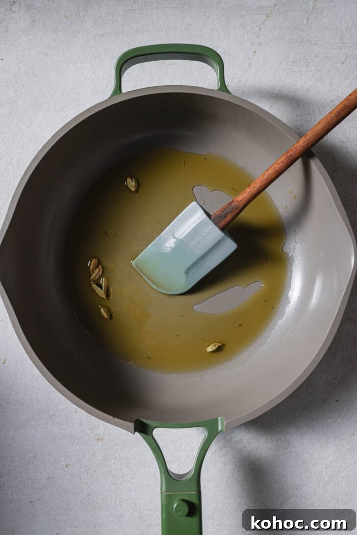 Melted ghee in a skillet with green cardamom.