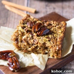 Baked pecan pie oatmeal on a wood slab with cinnamon sticks in the background.