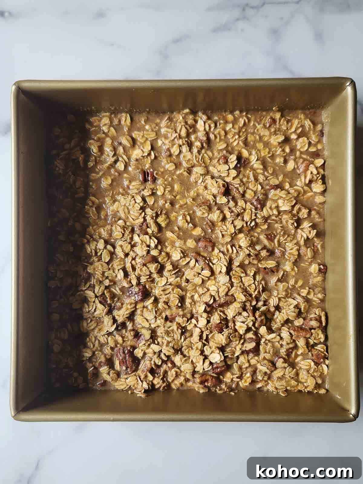 Prepared batter for pecan pie oatmeal in a square pan.