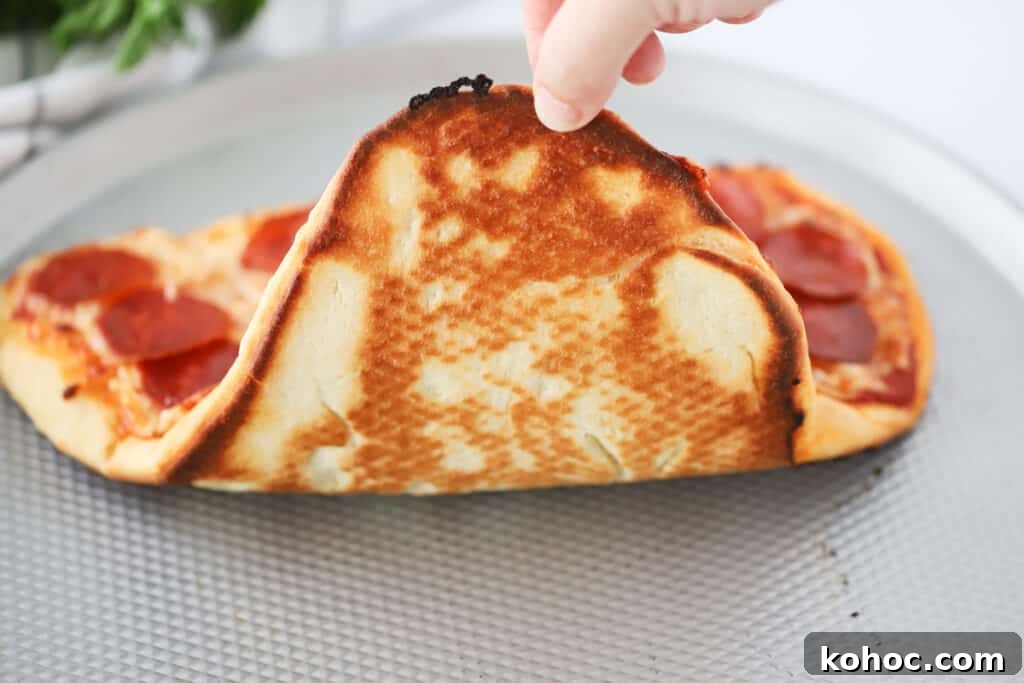 Make a Heart-Shaped Pizza at Home: Step-by-Step Recipe and Tips 5 A hand holding up a baked pizza to check the bottom.