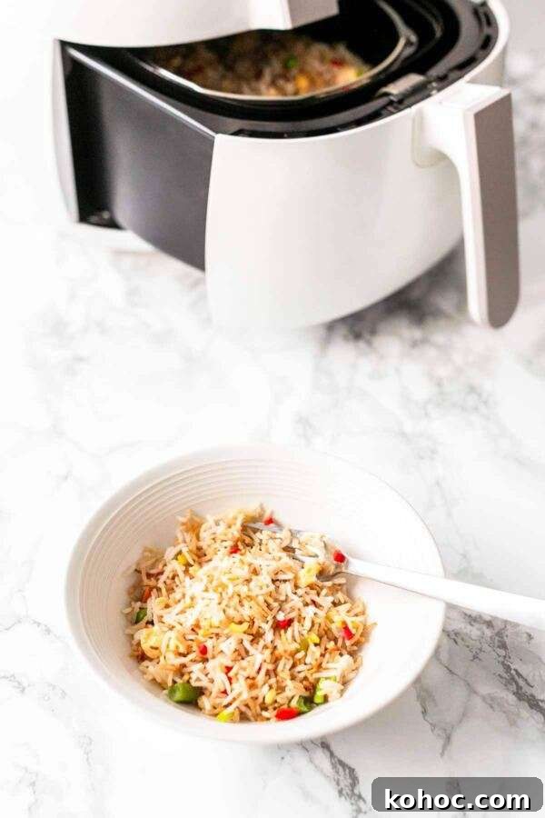 Crispy Air Fryer Fried Rice Recipe for Quick Weeknight Meals 7 Air Fryer fried rice in a white bowl with a spoon. Ready to be served as a tasty side dish with dinner.