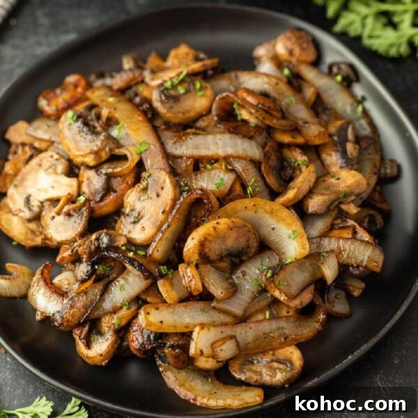 Blackstone Grilled Corn on the Cob in the Husk - Juicy BBQ Flavor 12 A black plate filled with Blackstone Sautéed Mushrooms and Onions for Steak, garnished with chopped herbs, sits on a dark surface.