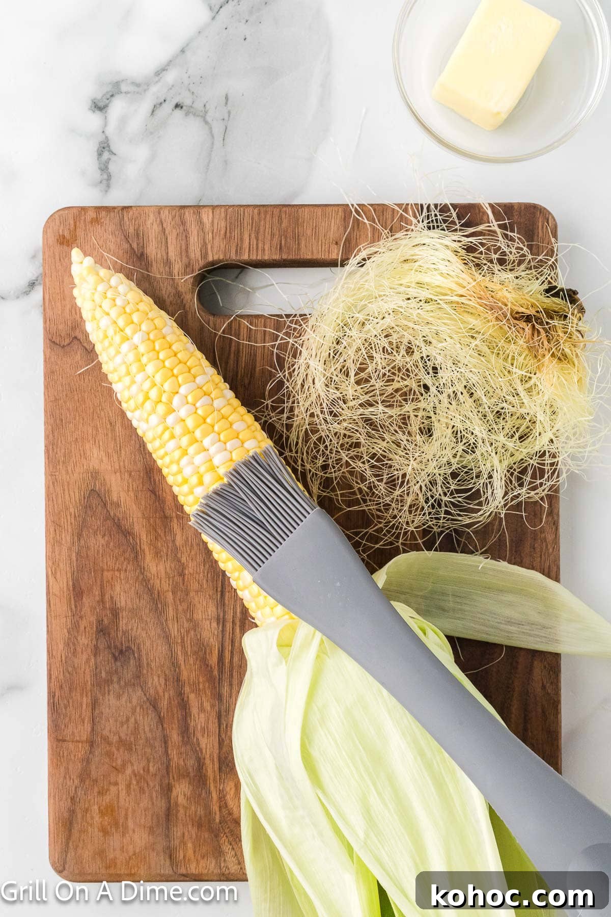 Blackstone Grilled Corn on the Cob in the Husk - Juicy BBQ Flavor 6 Brushing butter on the corn on the cob with the silk removed