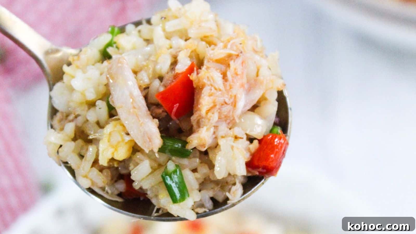 25 Skillet Meals Ready in 30 Minutes or Less 2 Close-up of a spoon holding fried rice with crab meat, green onions, and red bell peppers.