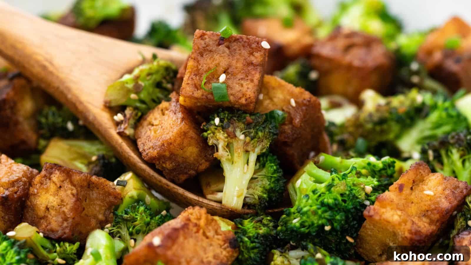 25 Skillet Meals Ready in 30 Minutes or Less 12 Roasted broccoli and tofu cubes garnished with sesame seeds and green onions, served with a wooden spoon.