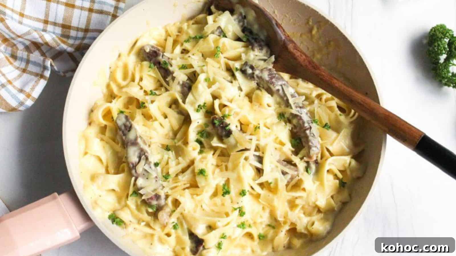 25 Skillet Meals Ready in 30 Minutes or Less 19 Alfredo steak pasta in skillet with wooden spoon.