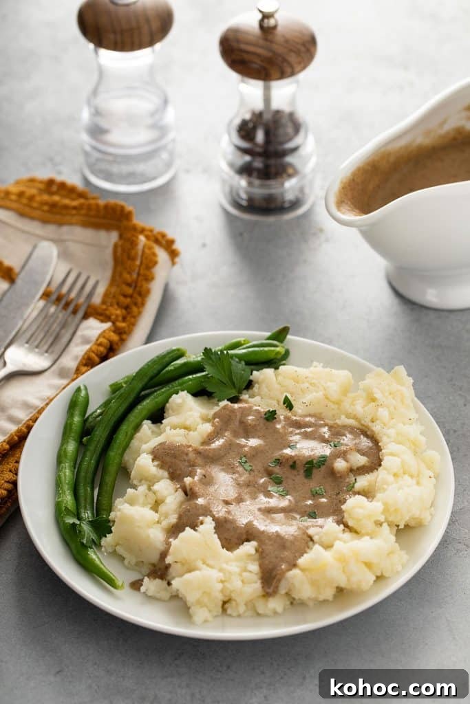 Savory Mushroom Vegan Gravy Recipe for Holiday and Everyday Meals 12 Vegan gravy over mashed potatoes served in a white plate with green beans.