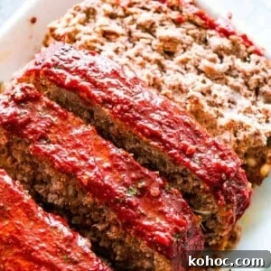 A sliced meatloaf with tomato glaze on a white serving plate.