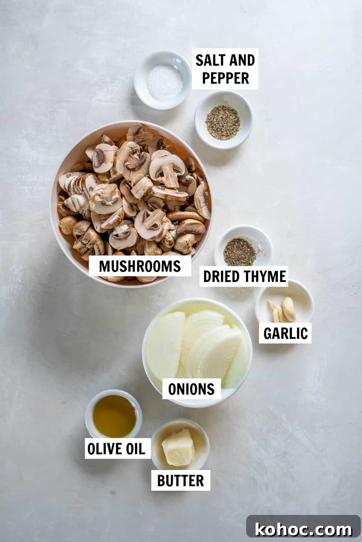 All of the ingredients for sauteed mushrooms and onions on a white countertop including mushrooms, onion, garlic, olive oil, salt, pepper and thyme.