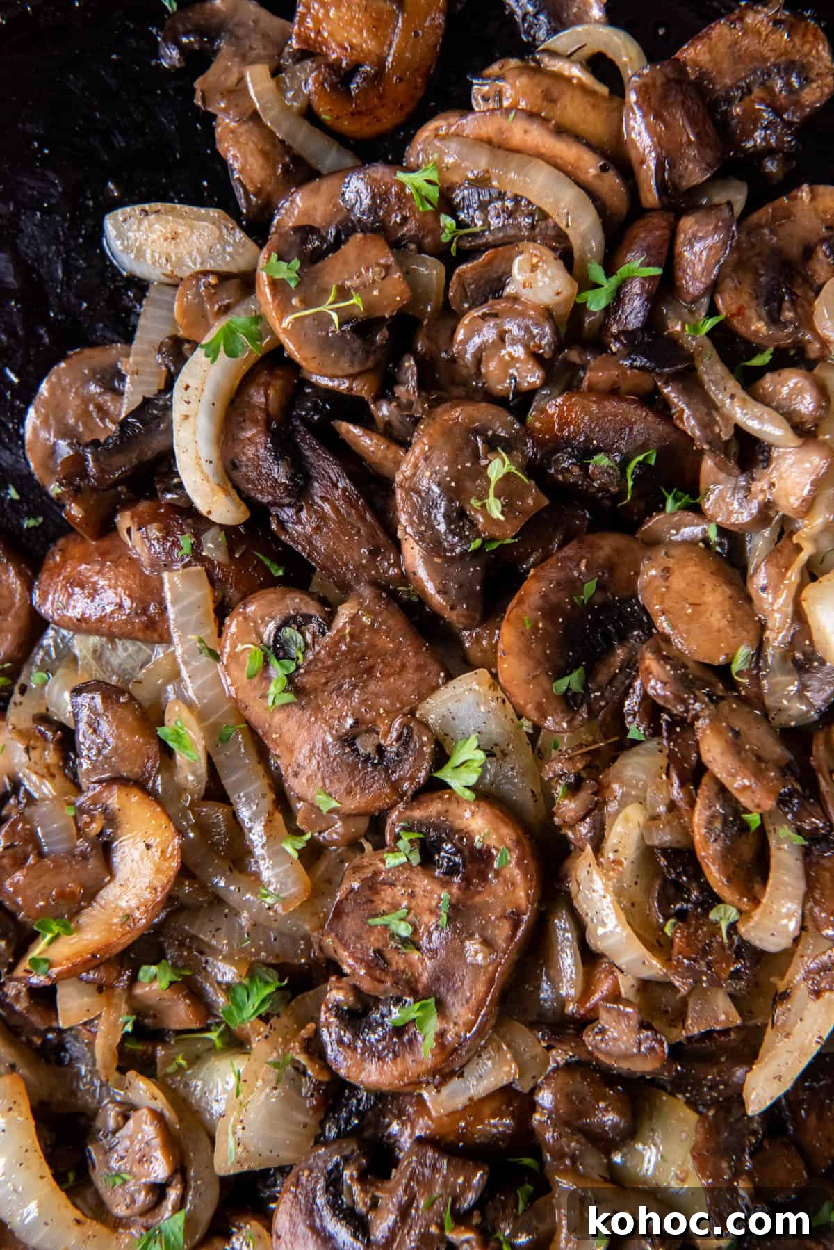 Cooked mushrooms and onions in a black cast iron skillet.