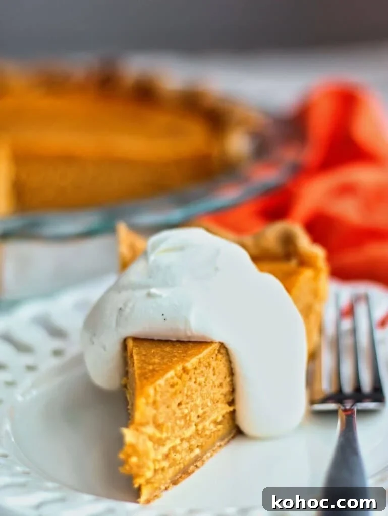 Gluten-Free Cream Cheese Pumpkin Pie Recipe 2 slice of gluten free pumpkin pie with whipped cream on white plate with orange cloth napkin in the background.