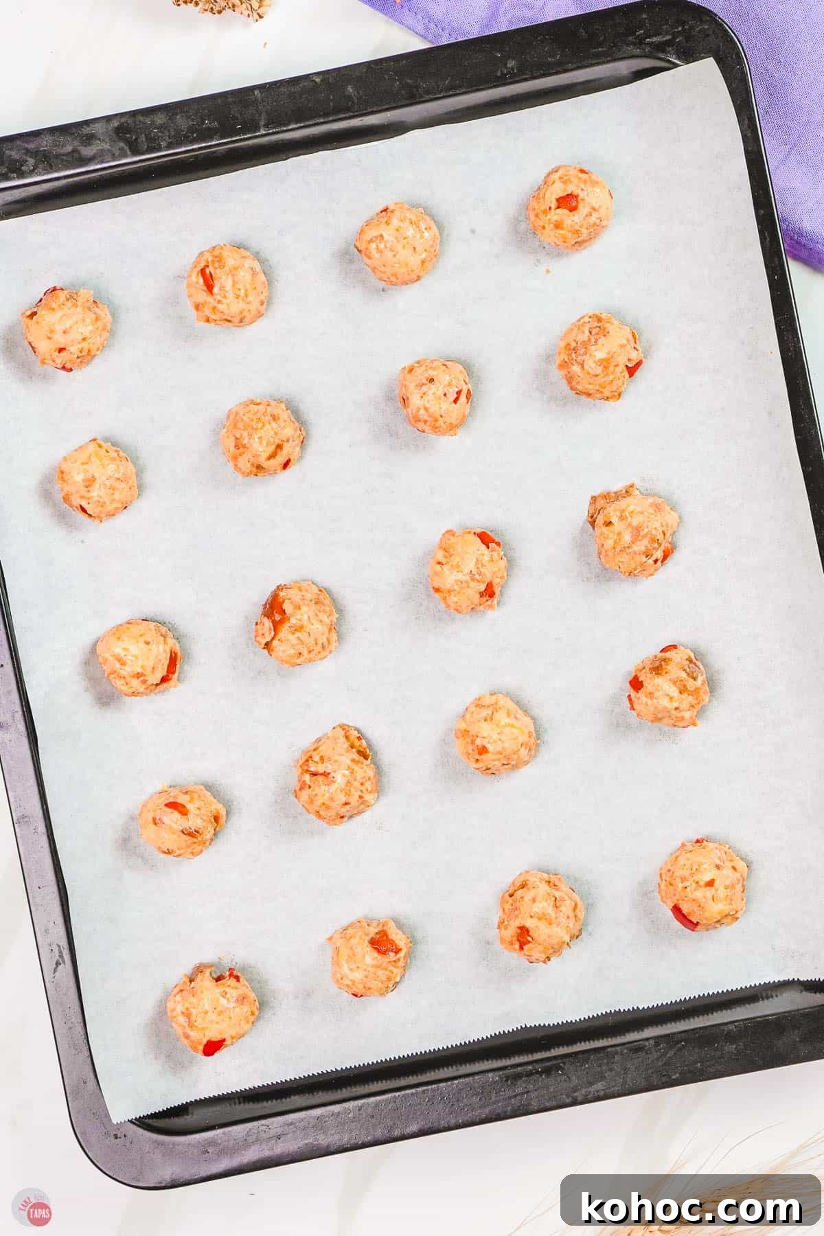 Pimento Cheese Sausage Balls: Southern Party Appetizer Recipe 5 unbaked pimento cheese sausage balls on a baking sheet lined with parchment paper