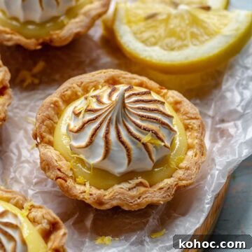 Mini lemon meringue tart on a tray with lemons.