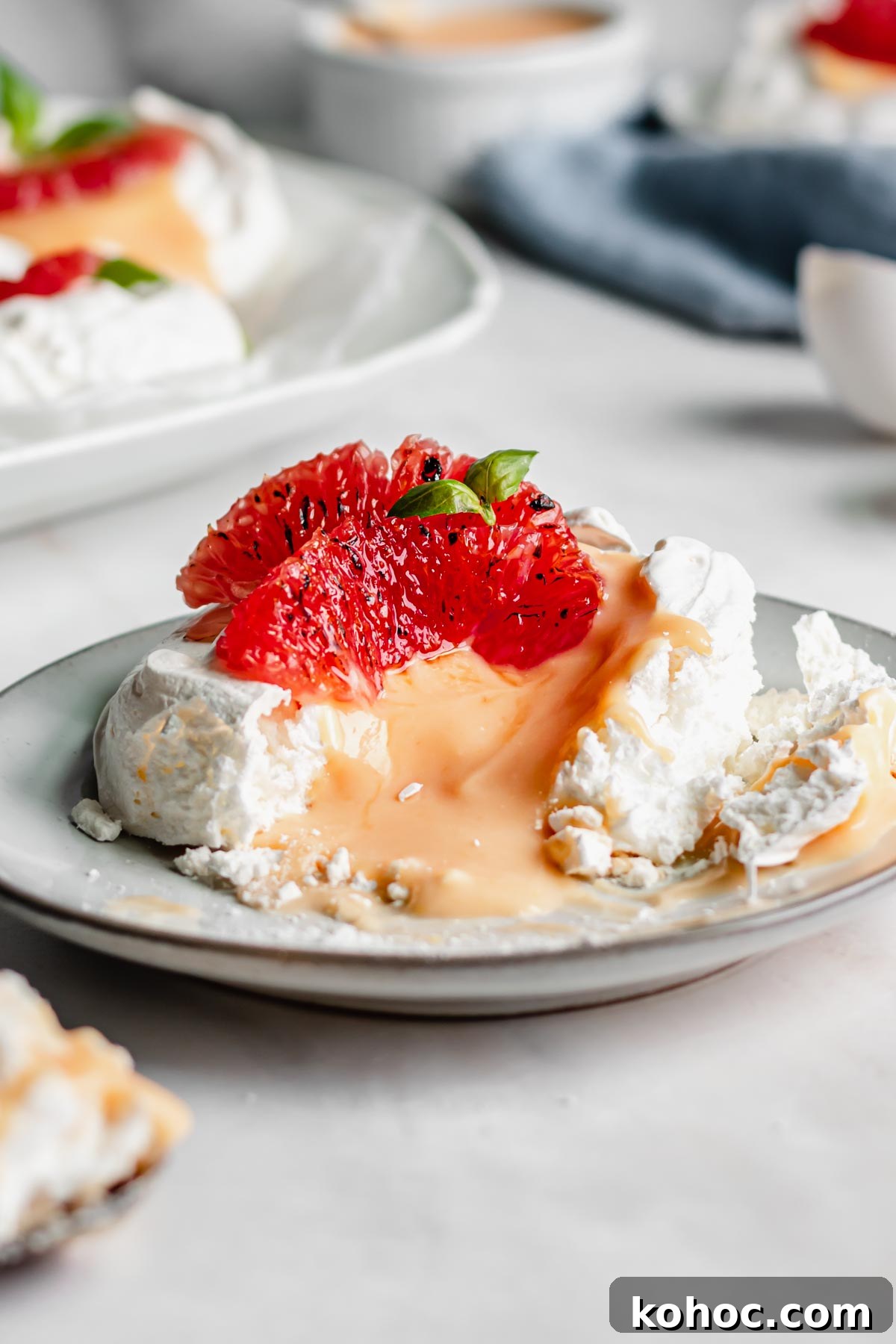 A single pavlova on a plate with a bite removed and the curd running out.
