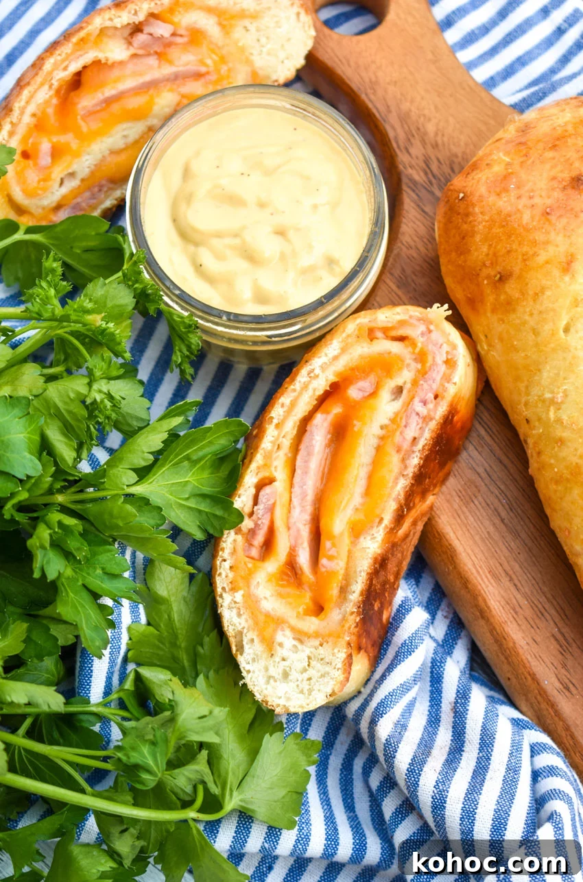 Ham and Cheese Stromboli Recipe: Crispy, Melty and Simple 2 slices of ham and cheese stromboli on a wooden cutting board