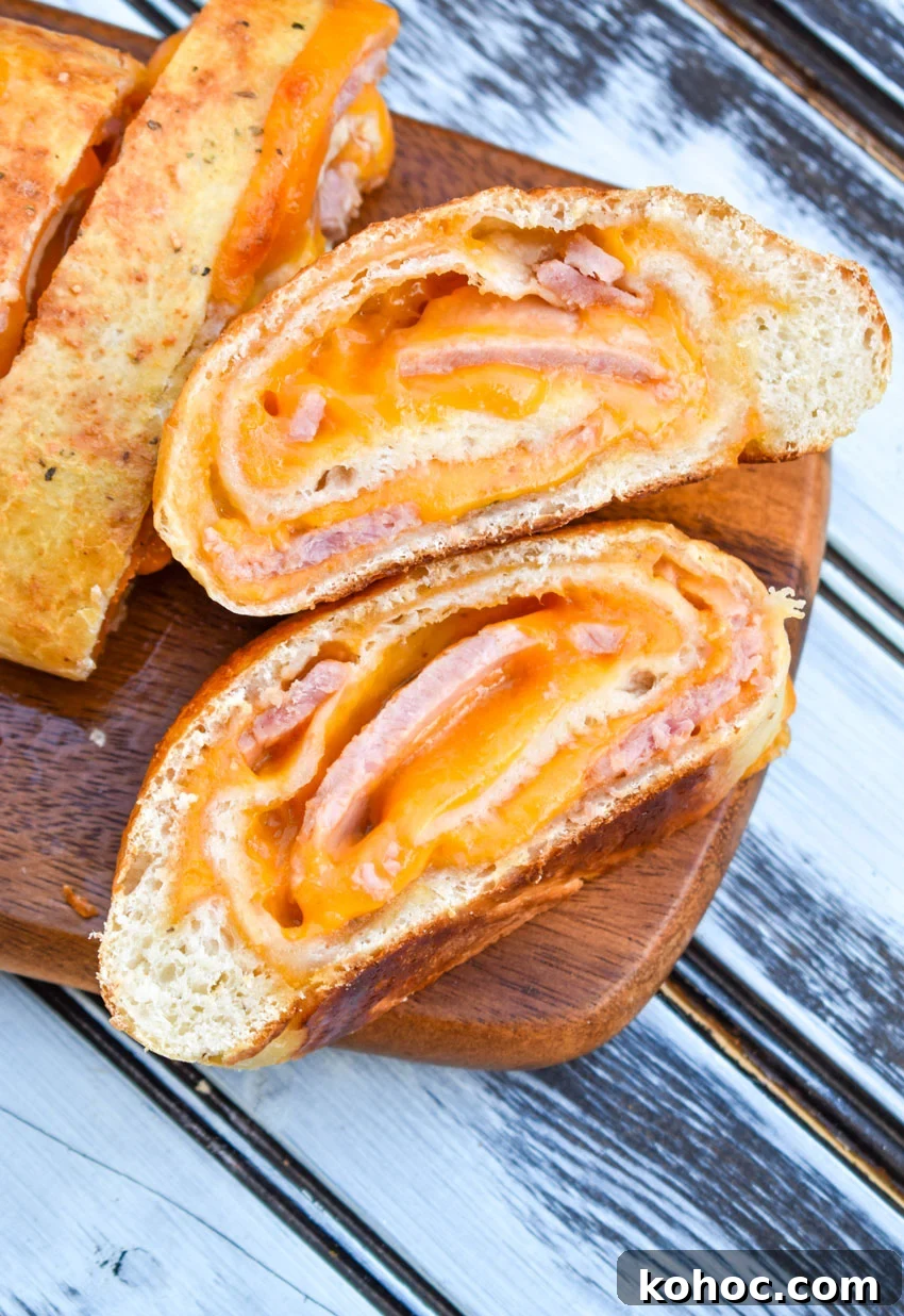 Ham and Cheese Stromboli Recipe: Crispy, Melty and Simple 3 slices of ham and cheese stromboli on a wooden cutting board