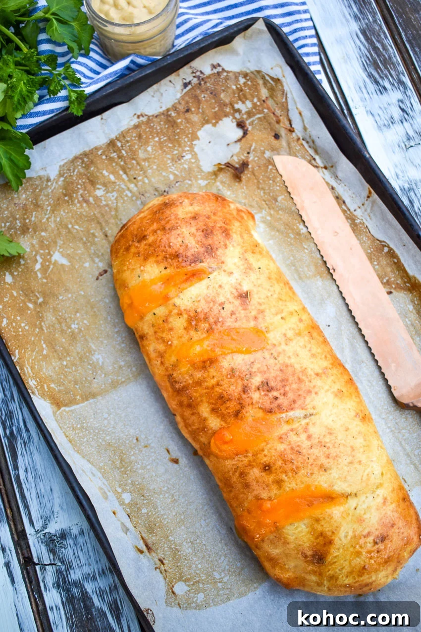 Ham and Cheese Stromboli Recipe: Crispy, Melty and Simple 4 a baked ham and cheese stromboli on a parchment paper lined baking sheet