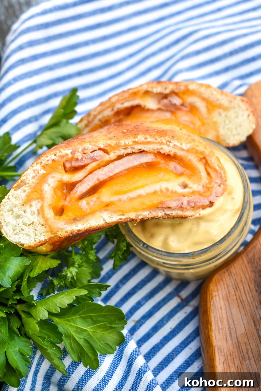 Ham and Cheese Stromboli Recipe: Crispy, Melty and Simple 5 a slice of ham and cheese stromboli being dipped into a glass jar filled with honey mustard