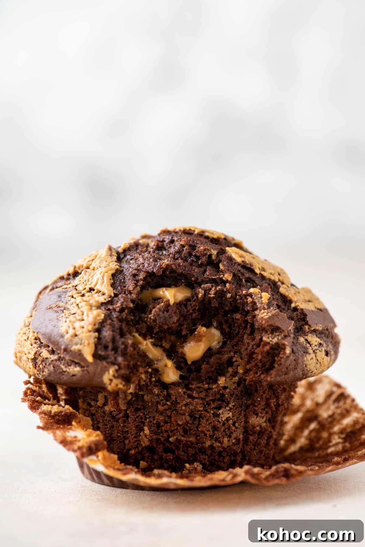 one chocolate peanut butter muffin with the muffin liner peeled partially off and a bite taken out