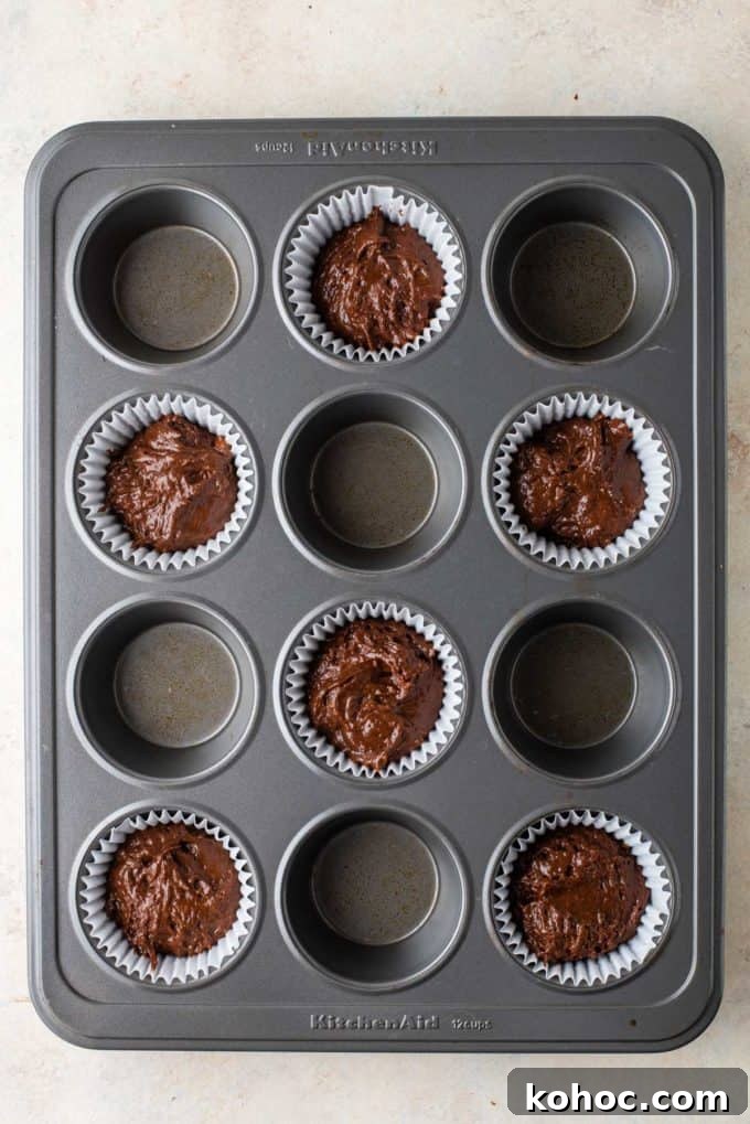 chocolate muffin batter in the bottom of muffin papers in every other hole of a muffin pan