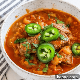 Steak green chili in a bowl with jalapenos.