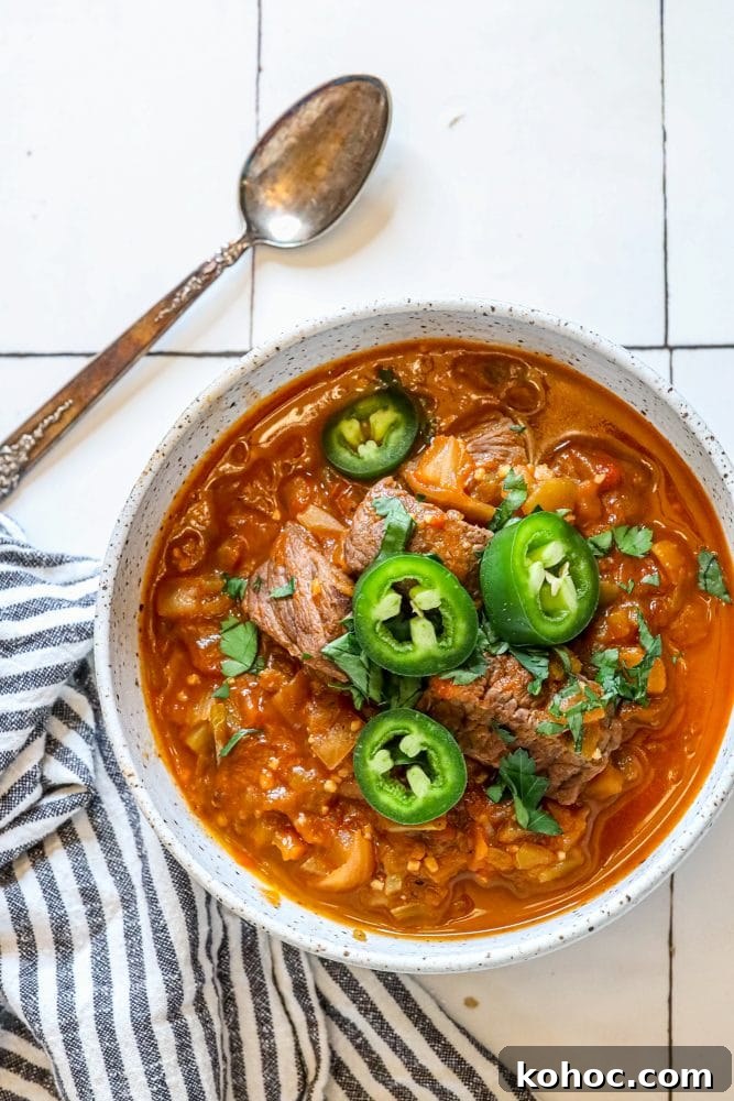 beef green chile with sliced jalapenos and chopped cilantro in a bowl 