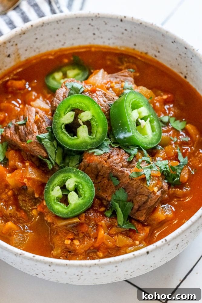 beef green chile with sliced jalapenos and chopped cilantro in a bowl 