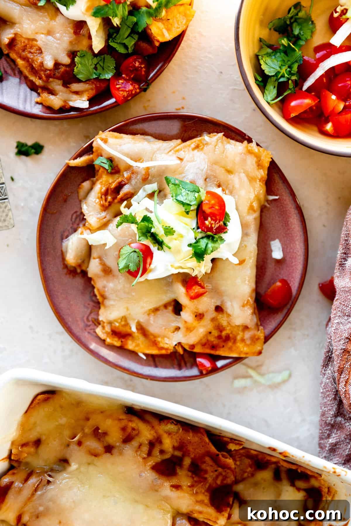 Tex-Mex Cheese Enchiladas with Melted Cheddar and Salsa Verde 7 Plated cheese enchiladas topped with sour cream, cilantro and diced tomatoes.