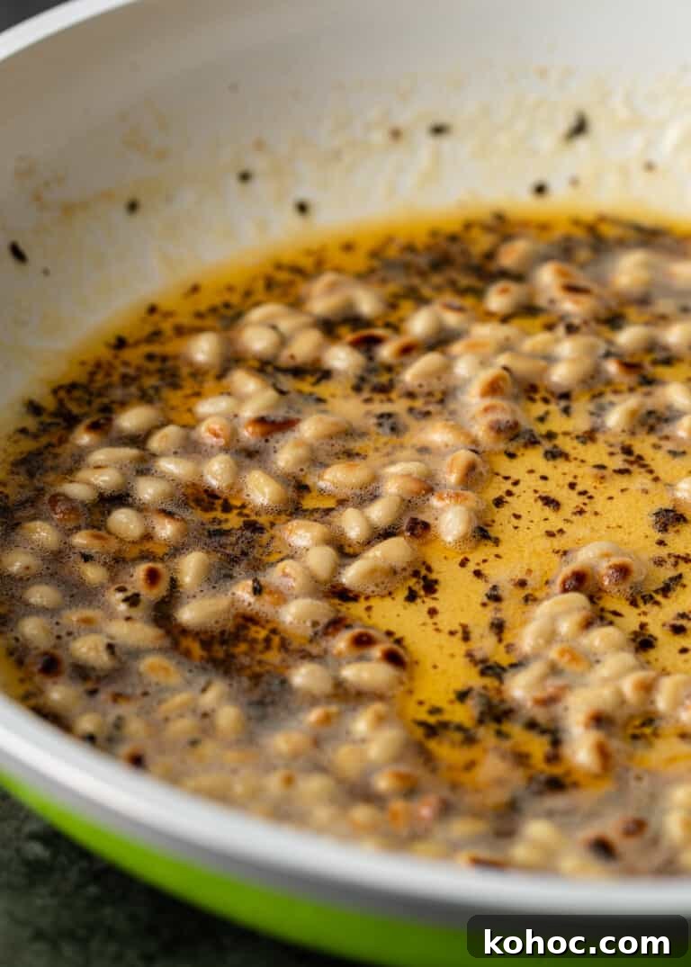 Shish Barak: Lebanese Lamb Dumplings in Yogurt Sauce 13 closeup: pine nuts in bowl with butter