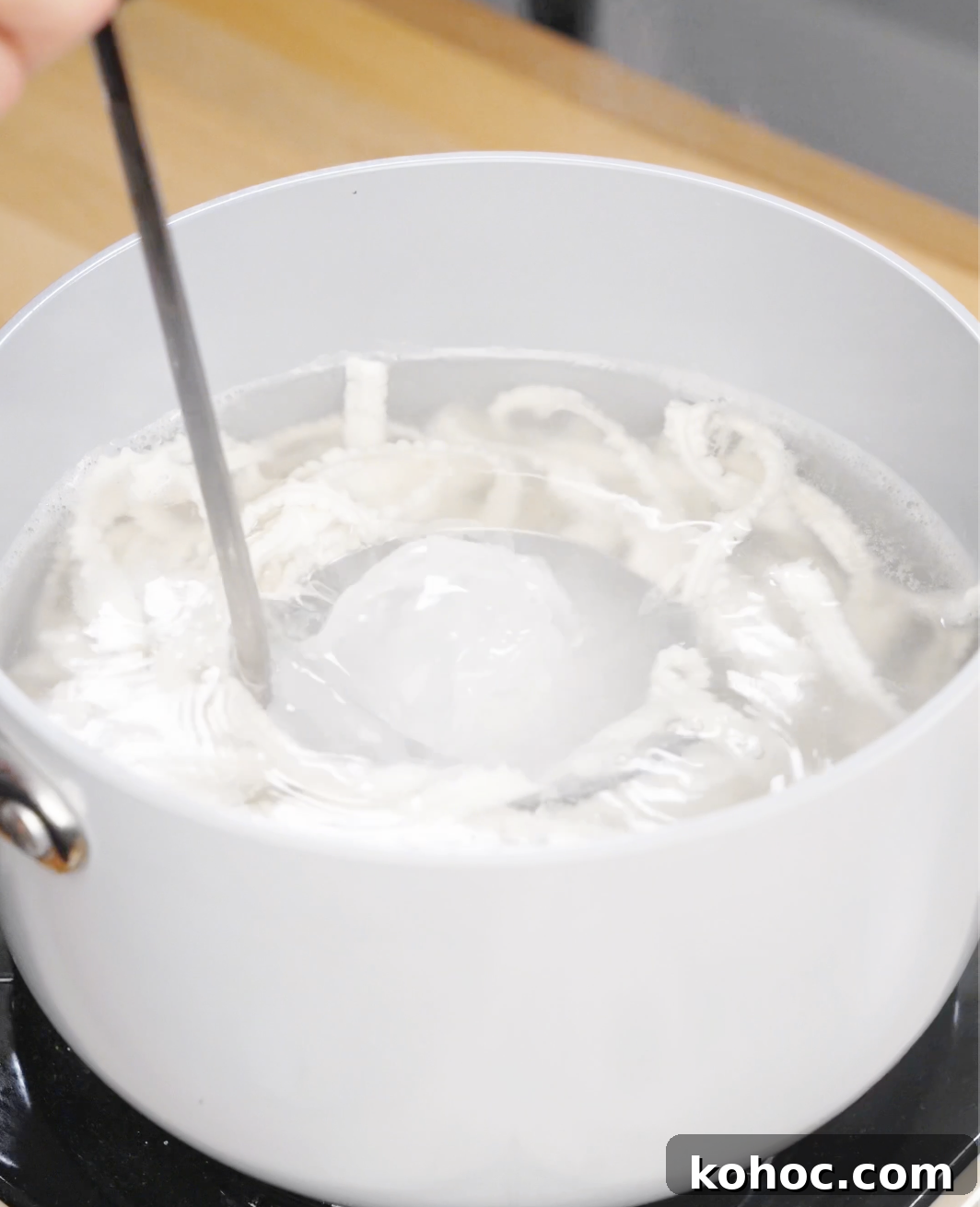 A ladle reserves starchy noodle water for Garlic Chili Noodles to help thicken and emulsify the sauce.