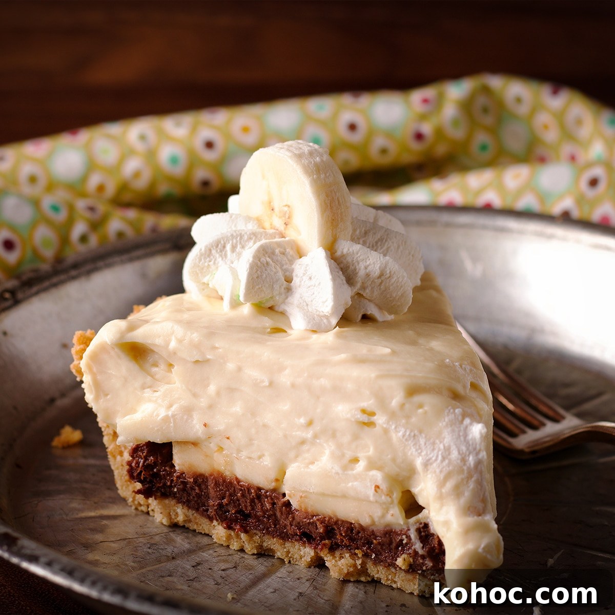 A slice of black bottom banana cream pie on a tin plate.