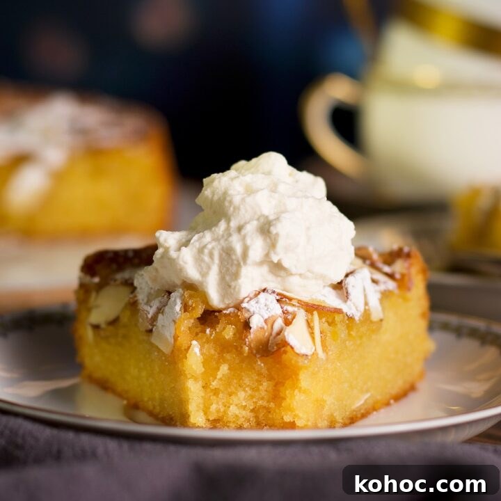 A slice of almond cake topped with whipped cream with a bite taken out of it.
