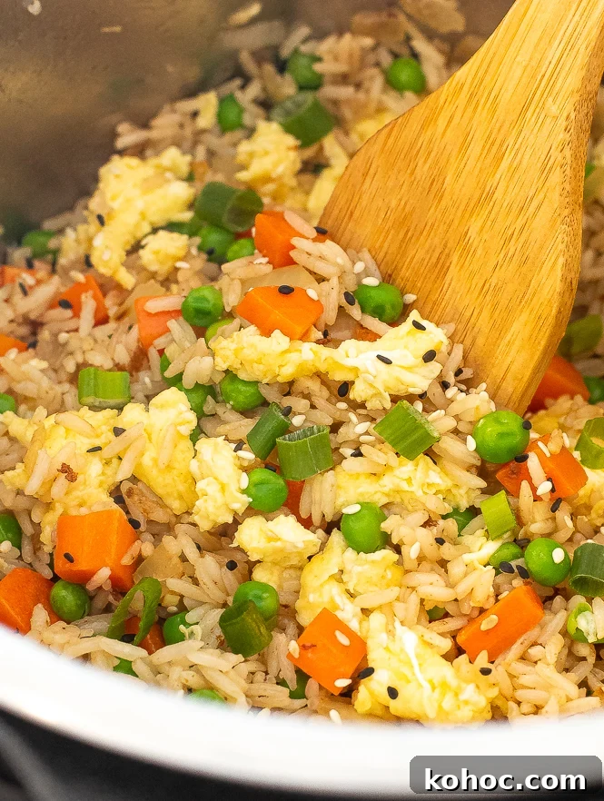 Perfect Instant Pot Fried Rice Recipe for Quick Weeknight Meals 3 Close up shot of fried rice being stirred by a wooden spoon.