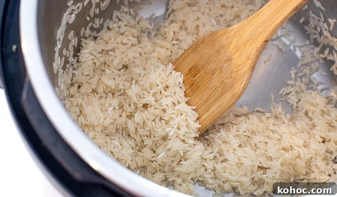 Perfect Instant Pot Fried Rice Recipe for Quick Weeknight Meals 5 Uncooked rice being sautéed in an instant pot with a wooden spoon.