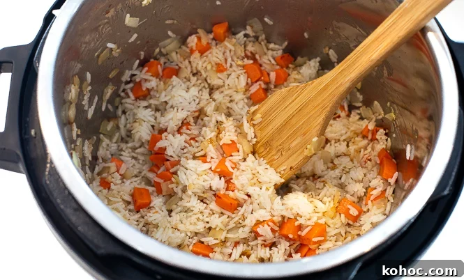 Perfect Instant Pot Fried Rice Recipe for Quick Weeknight Meals 8 Rice, onions and carrots in an instant pot with a wooden spoon.