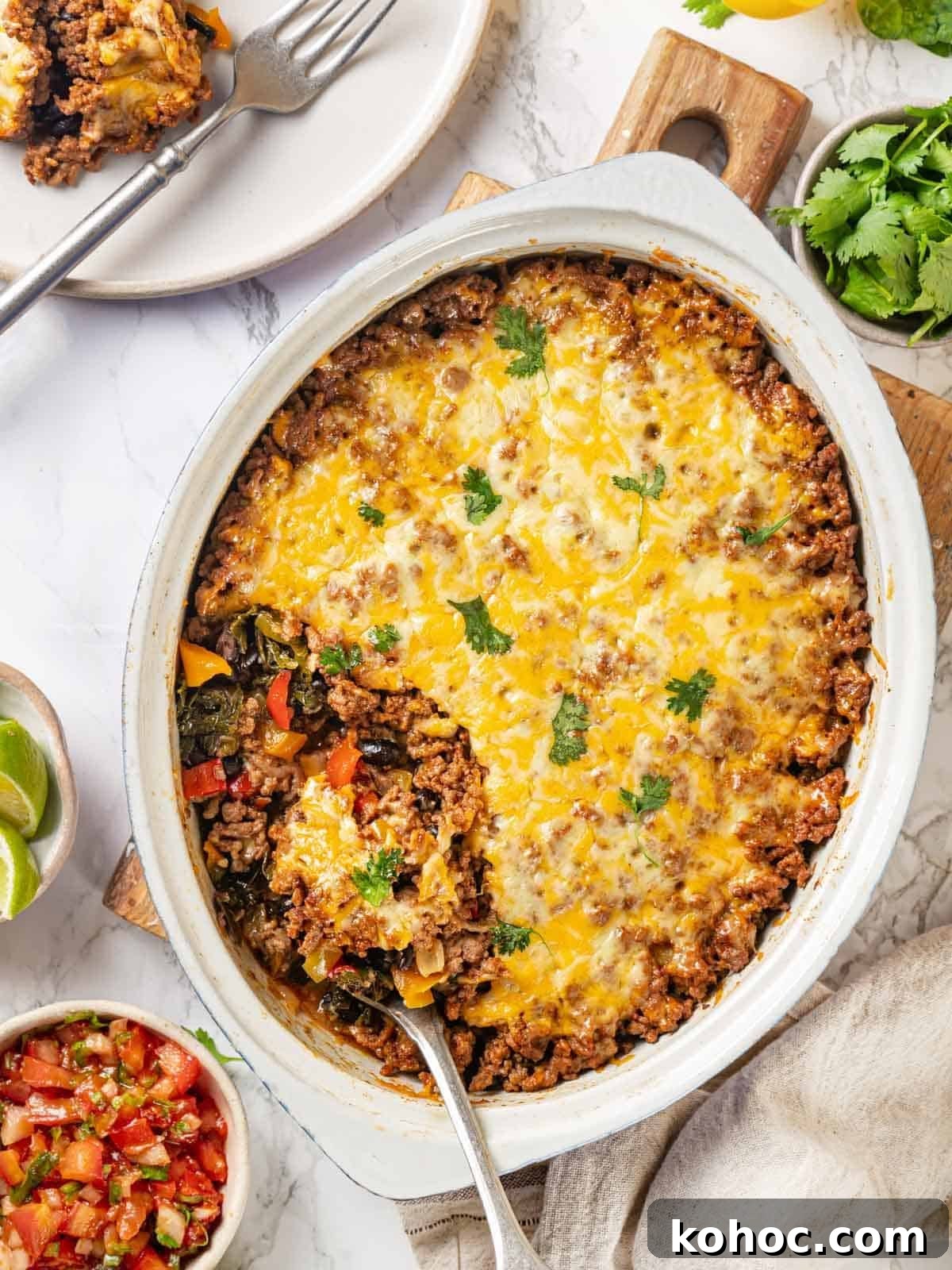 Cheesy Taco Casserole Bake with Ground Beef and Corn 14 taco bake in white serving dish with silver spoon.