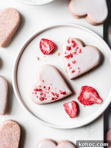 Glazed heart shaped cookies on a plate and a marble board.