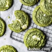 Matcha White Chocolate Cookies Recipe for Soft, Chewy Treats 16 A close up of green drop cookies with white chocolate chunks on a metal cooling rack.