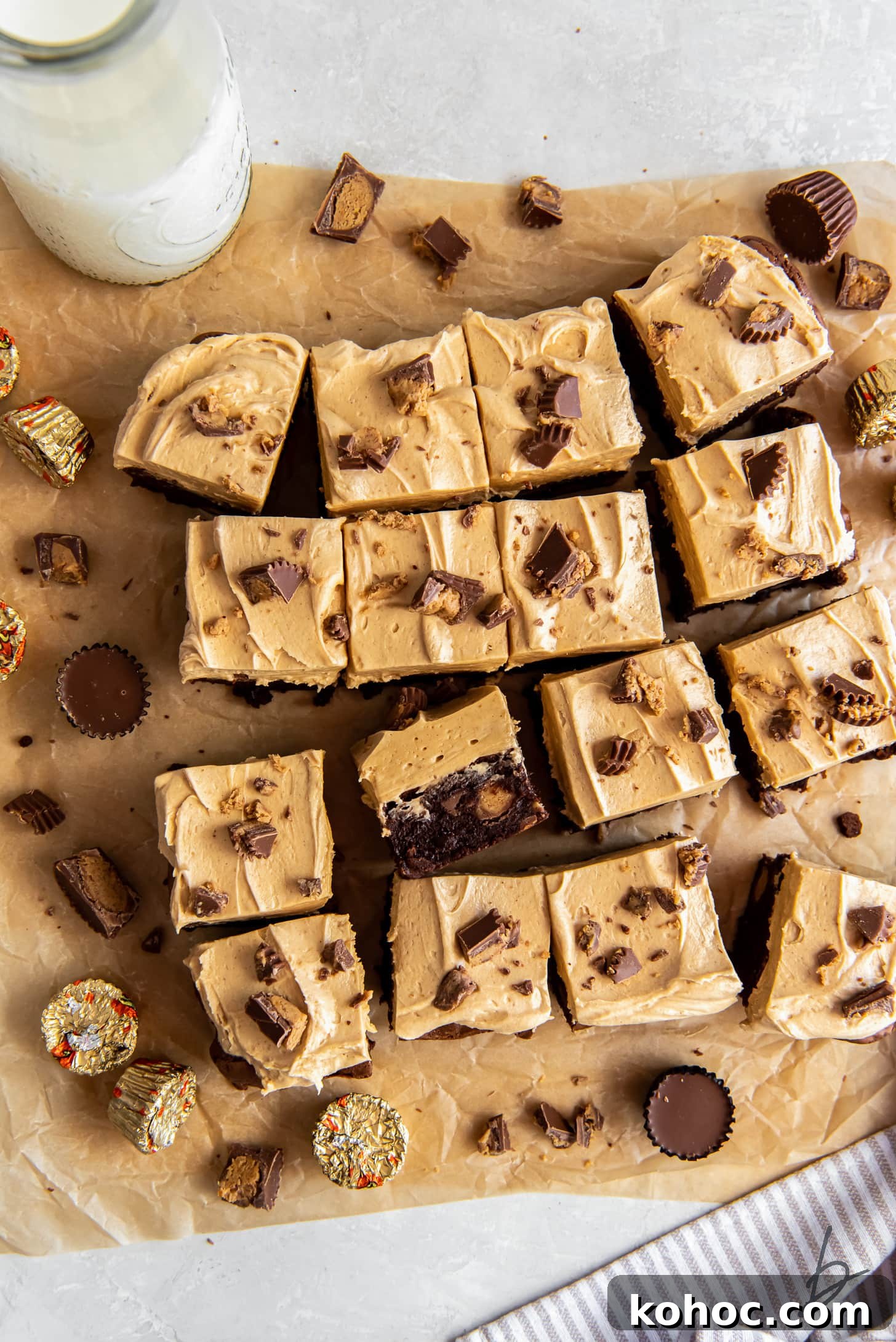 Frosted Peanut Butter Brownies Recipe — Rich Fudgy Chocolate Bars 6 peanut butter brownies with frosting and peanut butter cups on parchment paper.
