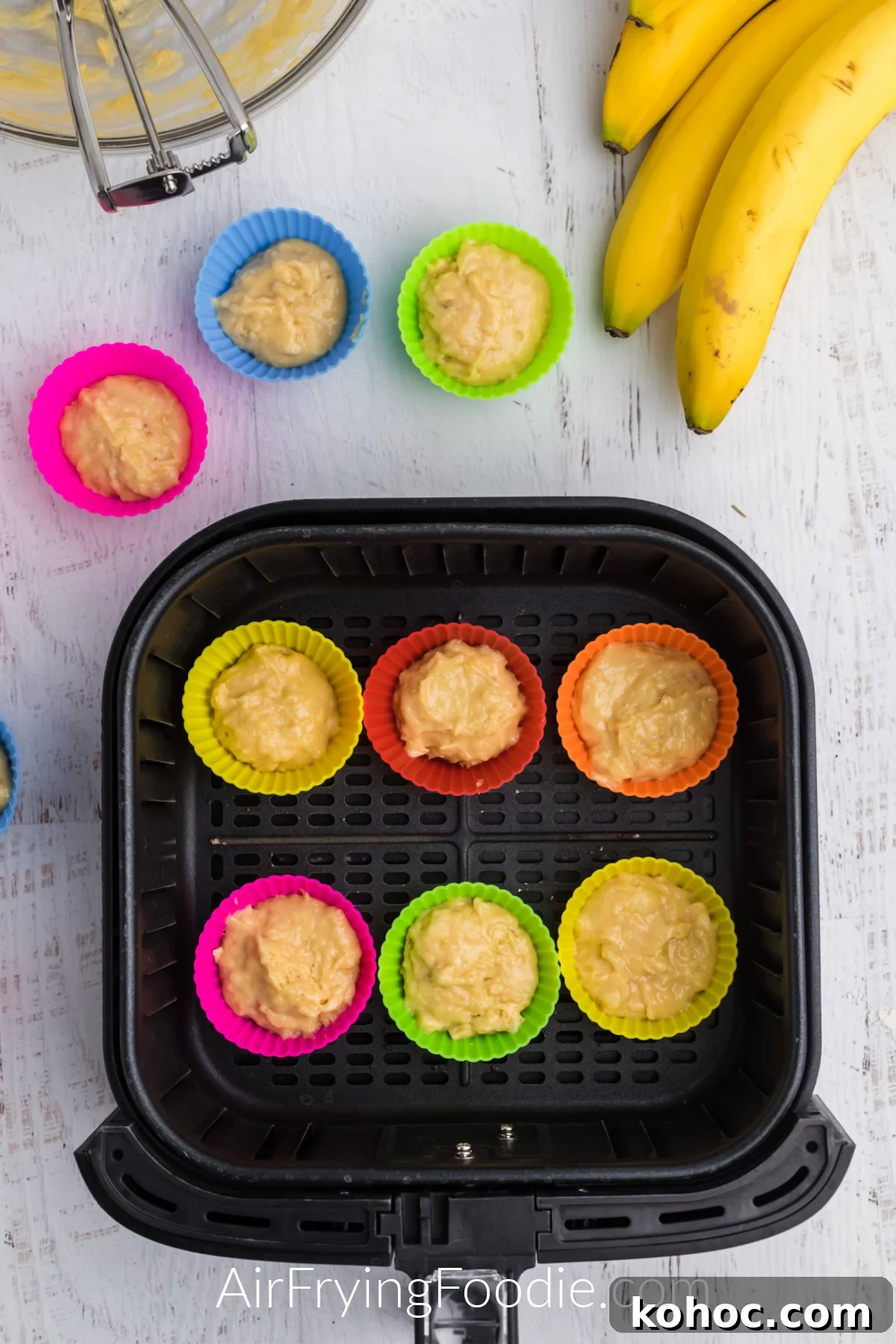 Banana muffin batter in silicone cups in the basket of the air fryer.