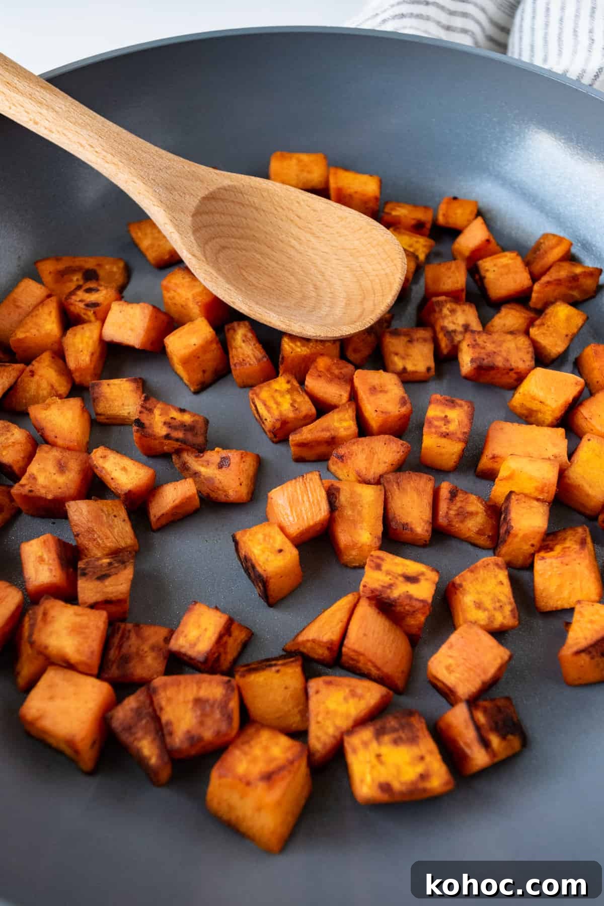 Crispy Sautéed Sweet Potatoes with Garlic and Herbs 4 Sautéed Sweet Potatoes in a skillet with a wooden spoon.