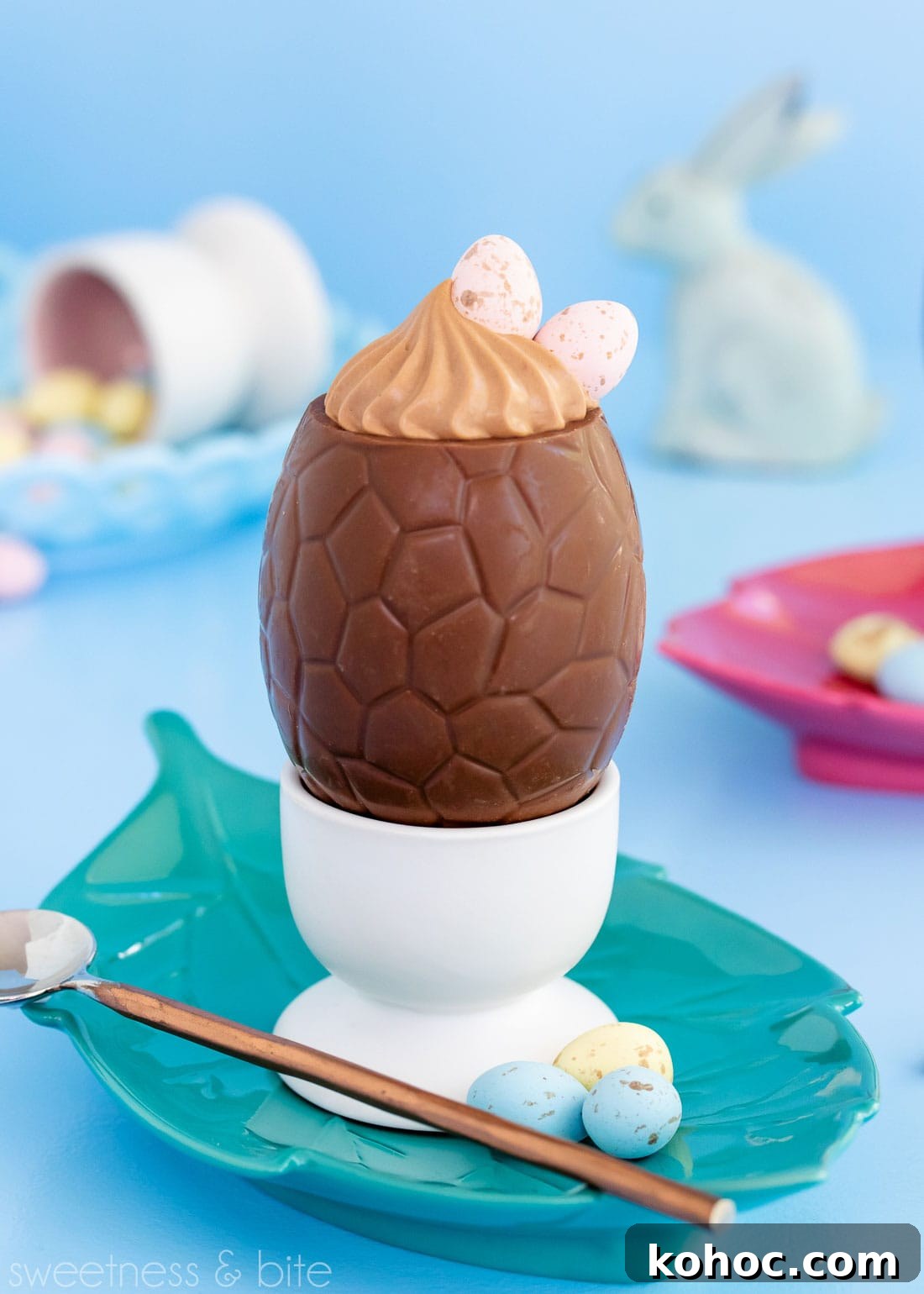 Milk Chocolate Mousse Easter Eggs Recipe for Spring Celebrations 6 Milk chocolate mousse Easter egg in a white egg cup, on a green leaf-shaped plate, with a brass handled spoon.